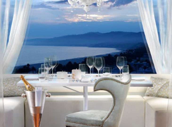 A Table With Glasses And A Glass On It With A View Of The Ocean And Mountains In The